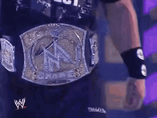 a man is wearing a wrestling belt with the letter w on it