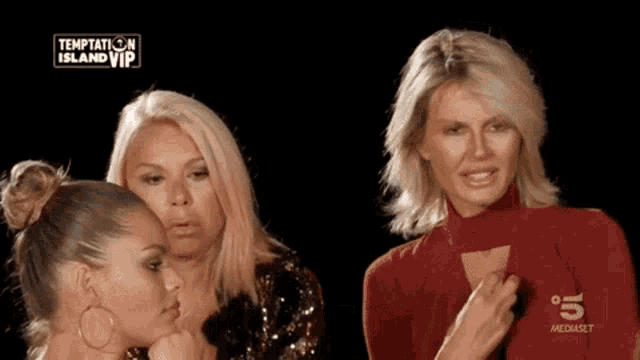 three women are standing in front of a screen that says temptation island vip on it