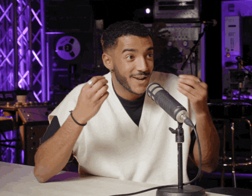 a man sitting in front of a microphone with his hands in the air