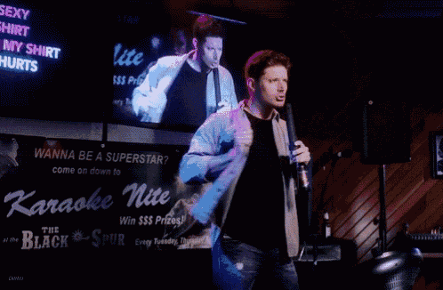 a man singing into a microphone in front of a sign that says " wanna be a superstar "