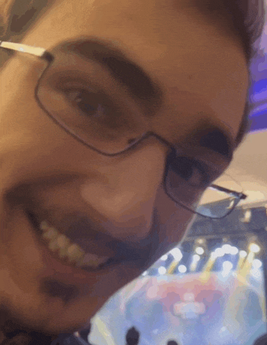 a close up of a man wearing glasses and smiling at the camera