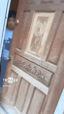 a man in a mask is standing in front of a wooden door with a picture on it .