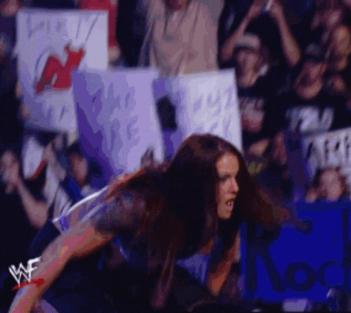 a wrestler is kneeling down in front of a crowd with a sign that says ' i love you ' on it