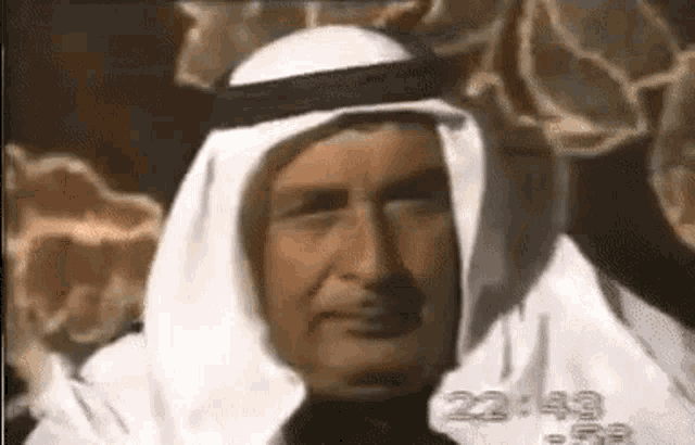 a close up of a man wearing a white robe and a black head scarf .