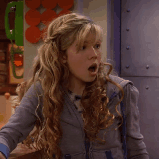 a girl with a surprised look on her face is wearing a gray jacket