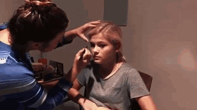 a woman is applying makeup to another woman 's face .