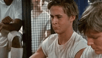 a young man in a white t-shirt is sitting next to another young man in a locker room .