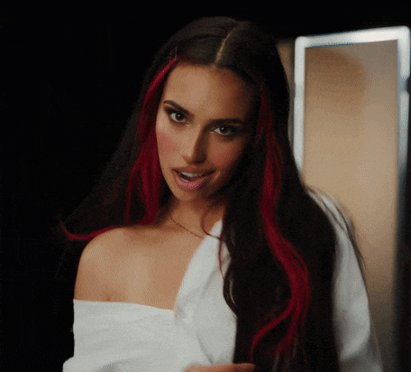 a woman with long dark hair and red streaks is wearing a white shirt