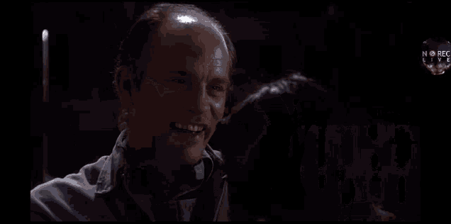 a man is being held by another man in a dark room with the words rec live on the bottom left