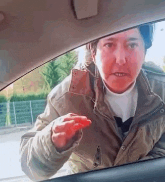a woman is sitting in the back seat of a car holding a red object in her hand .