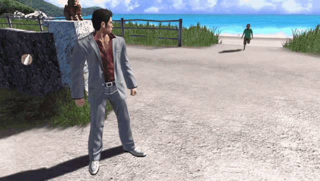 a man in a suit stands on a dirt road near a beach