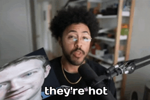 a man is holding a picture of a man in front of a microphone and says they 're hot