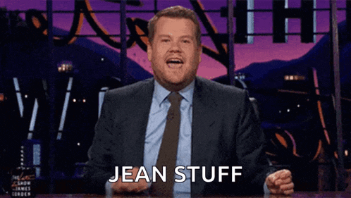 a man in a suit and tie is making a funny face and saying jean stuff .