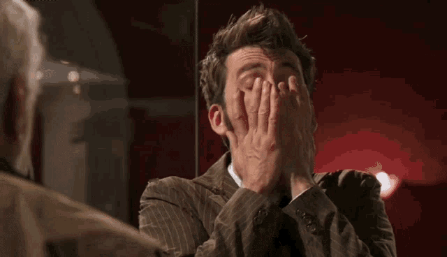 a man in a suit and tie is making a surprised face in front of a mirror