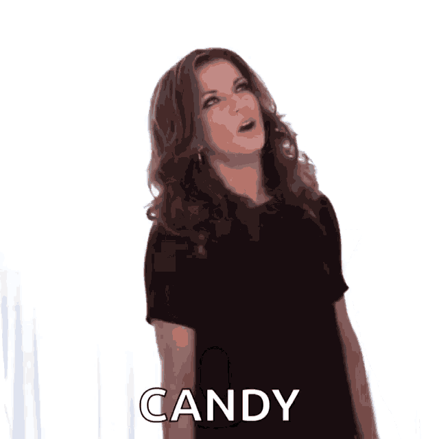 a woman in a black shirt is standing in front of a white curtain and says candy .