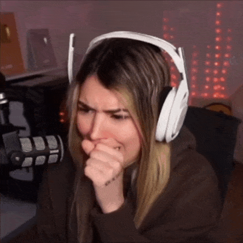 a woman wearing white headphones is covering her mouth