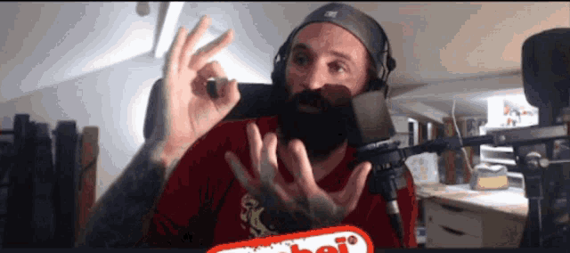 a man with a beard and headphones giving an ok sign