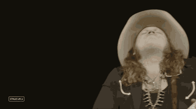 a man in a cowboy hat is playing a guitar in front of a sign that says stagelaga