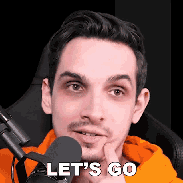 a man sitting in front of a microphone with the words let 's go on his face
