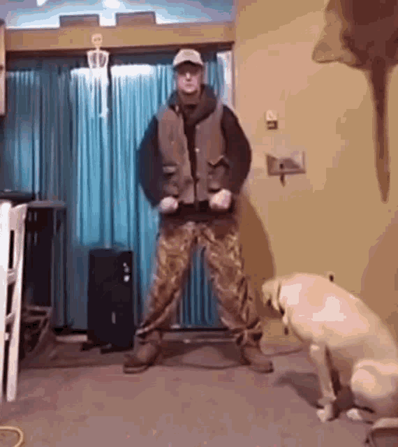 a man is dancing in a living room next to a dog .
