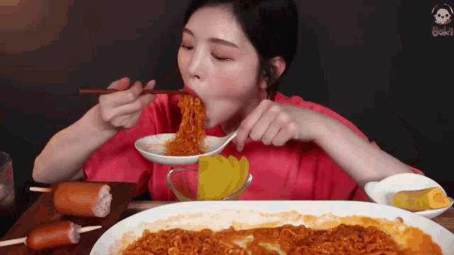 a woman is eating noodles with chopsticks from a bowl .