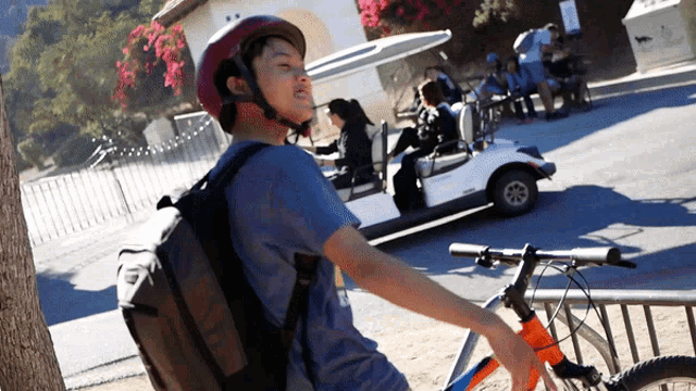 a boy wearing a helmet is standing next to a bicycle in front of a golf cart