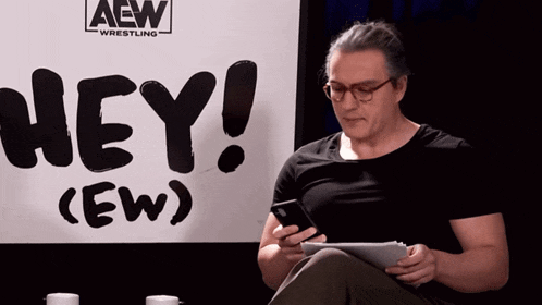 a man sitting in front of a sign that says hey ew