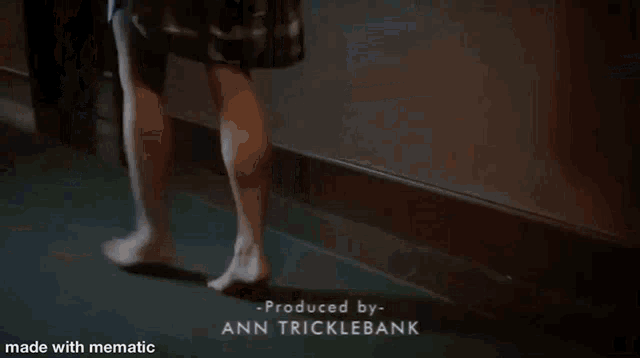a woman is walking down a hallway with the words produced by ann tricklebank at the bottom .