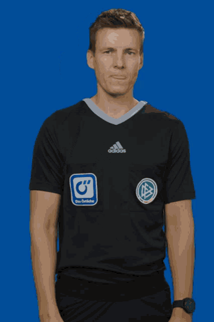 a man wearing a black adidas shirt is pointing up
