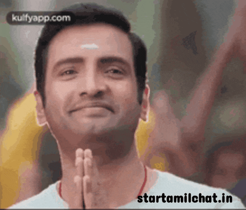 a man is smiling with his hands folded in prayer .