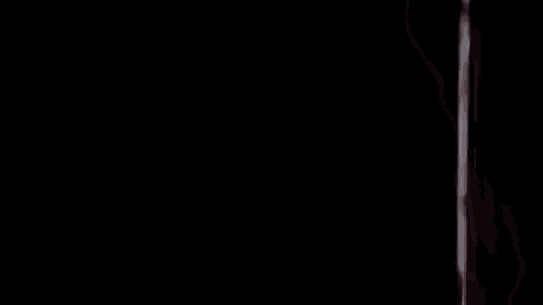 a woman with blonde hair is standing next to a man in a dark room and looking at the camera .