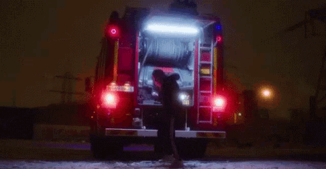 a man is standing in front of a fire truck in the snow .