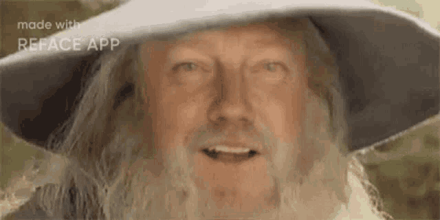 a man with a beard and a hat is smiling and looking at the camera .