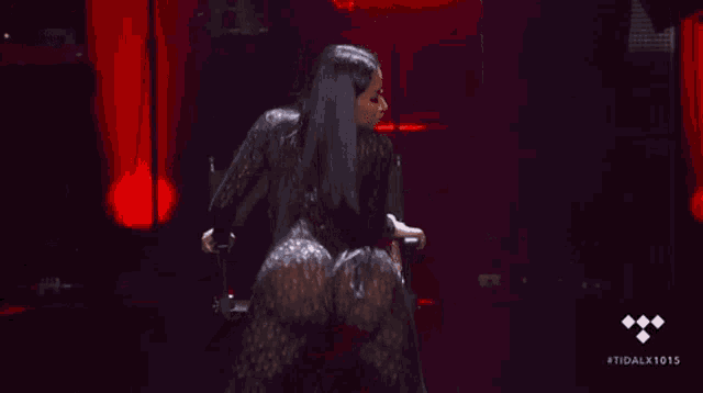 a woman in a black lace jumpsuit is dancing on stage