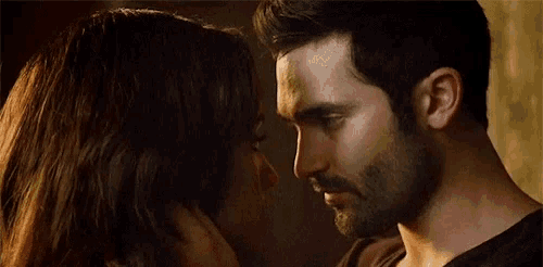 a man and a woman are kissing in front of a wall .