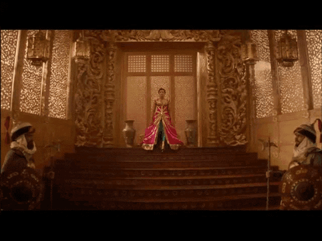 a woman in a red dress stands on a throne