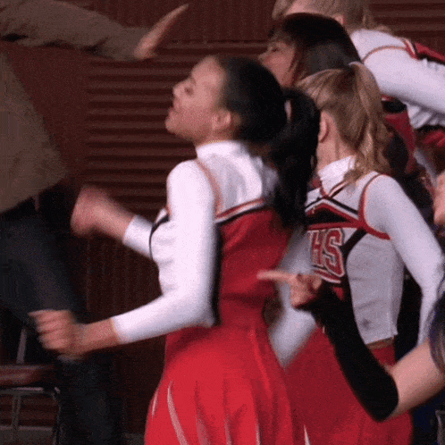 a group of cheerleaders wearing hs uniforms dancing