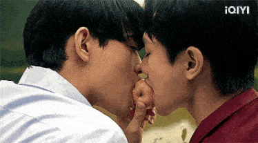 two young men are kissing while one of them is eating an apple