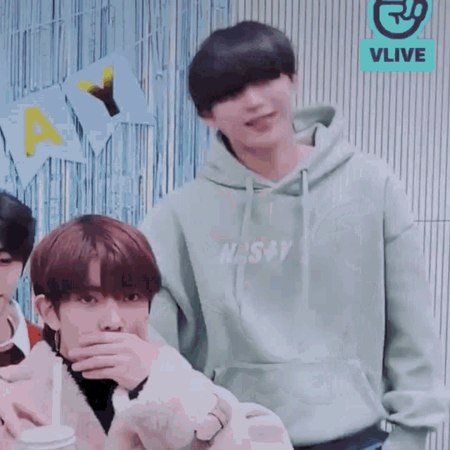 a man in a green hoodie is standing next to a boy in a white coat .