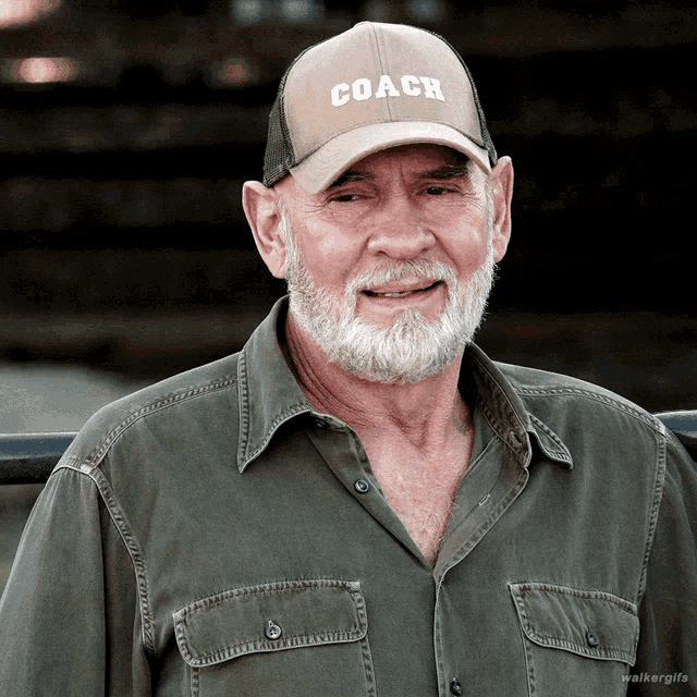 a man with a beard wears a coach hat