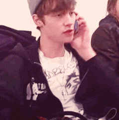 a young man talking on a cell phone while wearing a t-shirt that says angels on it