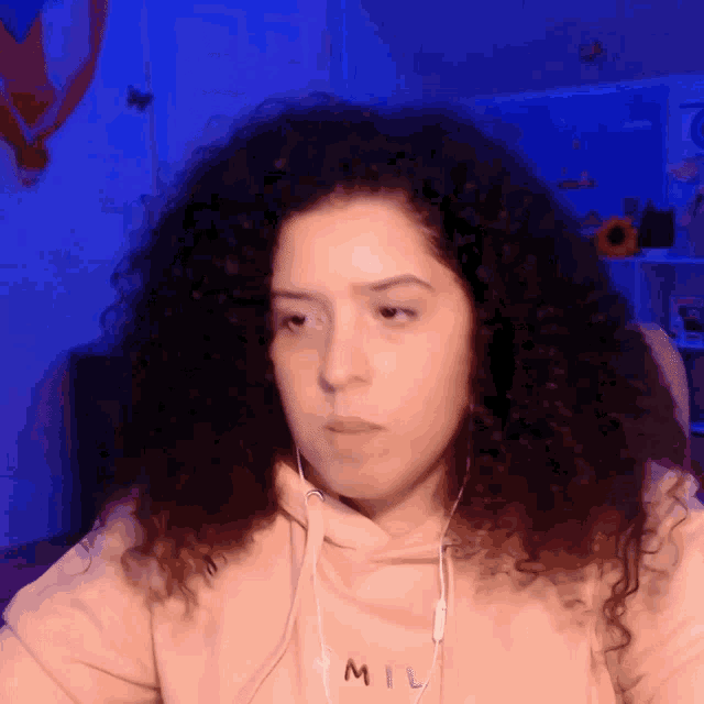 a woman with curly hair wears a mil sweatshirt