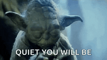 a close up of a statue of yoda with the words `` quiet you will be '' written below him .