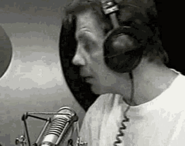 a man wearing headphones is sitting in front of a microphone .