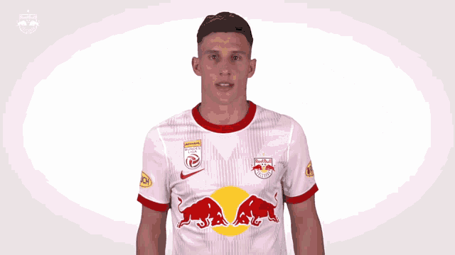 a soccer player wearing a red bull jersey giving a thumbs up