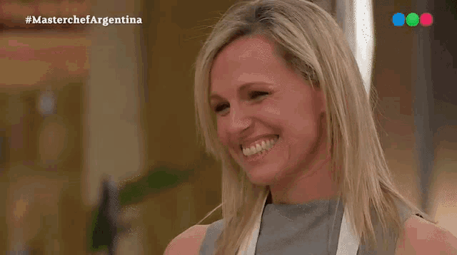 a woman is smiling in front of a screen that says masterchefargentina