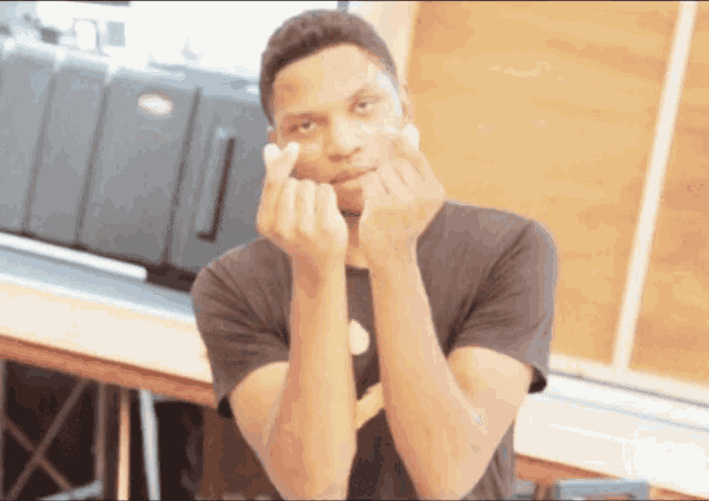 a man in a black shirt is making a funny face with his hands
