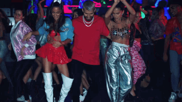 a man in a red shirt is dancing with a group of women
