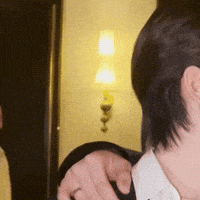 a man wearing a white shirt and a black jacket is looking at himself in a mirror