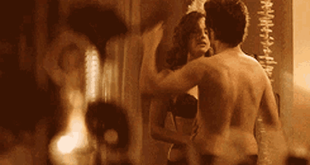 a man and a woman are standing in front of a mirror
